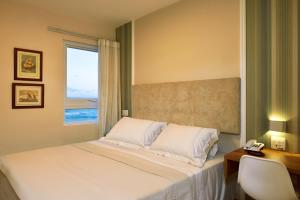 a bedroom with a bed and a desk and a window at Rede Andrade Express in Salvador