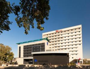 un hotel blanco con una señal roja encima en Ibis Gaziantep en Gaziantep