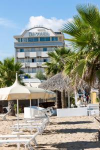 un hotel sulla spiaggia con sedie e palme di Hotel Du Soleil a Rimini