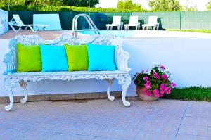 a white bench with colorful pillows sitting next to a tub at Quinta das Amendoeiras in Albufeira