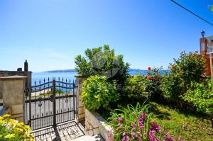 a garden with a fence and flowers and the water at Apartments Lucic in Senj