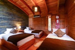 um quarto com 2 camas num quarto com paredes de madeira em Aldea Naukana Posada Boutique em Pucón