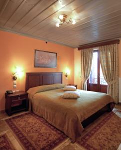 - une chambre avec un grand lit aux murs orange dans l'établissement Amanites Guesthouse, à Dimitsana