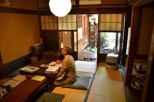 un homme assis à un bureau dans une pièce dans l'établissement Guest House Kingyoya, à Kyoto