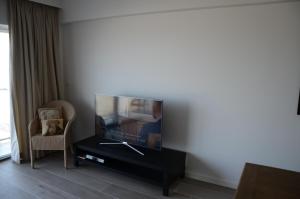 a living room with a flat screen tv and a chair at Apartment Beach in Blankenberge