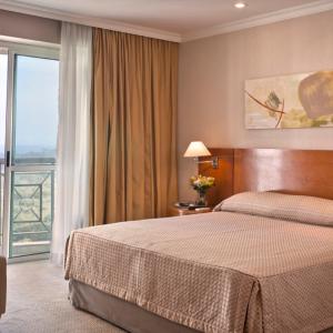 a hotel room with a bed and a large window at Bourbon Barra da Tijuca Residence in Rio de Janeiro