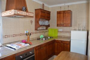 埃爾博斯克的住宿－ÁTICO CAHI，厨房配有木制橱柜和白色冰箱。