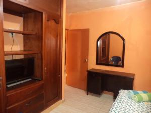 a bedroom with a bed and a tv and a mirror at Posada Nativa Shingle Hill in San Andrés