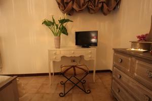 アルベロベッロにあるSuite del Vicoのデスク、テレビ、花瓶が備わる客室です。