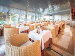 una sala da pranzo con tavoli e sedie bianchi di Park Hotel a Lignano Sabbiadoro
