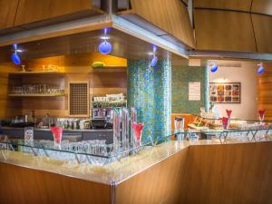 a restaurant with a bar with red vases on the counter at Park Hotel in Lignano Sabbiadoro