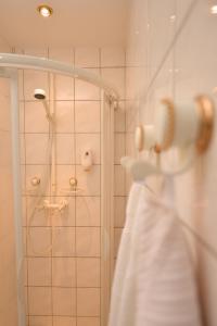 a bathroom with a shower with a white dress on a rack at Adler Golf-& Tagungshotel in Harth - Pöllnitz
