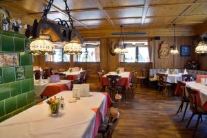 uma sala de jantar com mesas, cadeiras e lustres em Hotel Schöne Aussicht em Niederwasser