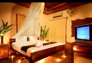 a bedroom with a bed and a television in it at Pai Love & Baan Chonphao Resort in Pai