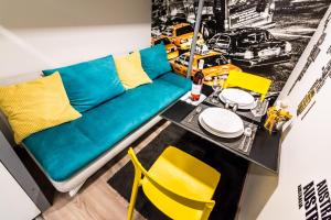 a living room with a blue couch and a table with yellow chairs at Klauzal Design Apartment in Budapest