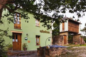 a green house with a tree in front of it at Os Tres Teixos in San Acisclo