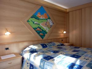 een kamer met een bed met een schilderij aan de muur bij Appartamenti Majon Sotroi in Campitello di Fassa