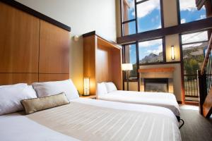 two beds in a hotel room with a fireplace at Sunshine Mountain Lodge in Banff