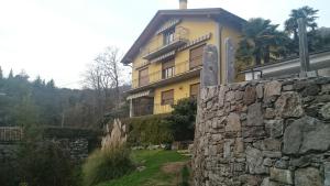 Una gran casa amarilla con una pared de piedra. en Casa dei Mulini, en Mergozzo