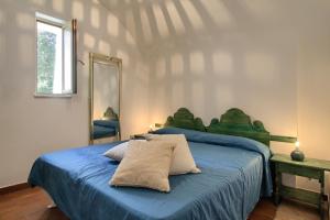Schlafzimmer mit einem Bett mit blauer Bettwäsche und einem Spiegel in der Unterkunft Scogliera del Gabbiano in Santa Maria di Leuca