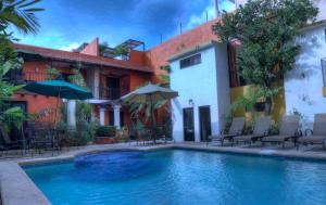 a swimming pool in front of a building with chairs and umbrellas at Hotel Luz en Yucatan in Mérida