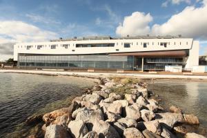 a building next to a body of water with rocks at Hôtel du Golfe Sete-Balaruc in Balaruc-les-Bains