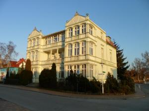 un gran edificio blanco sentado al lado de una calle en Hotel Schloonsee Garni en Bansin