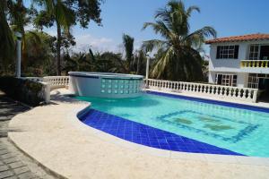 a swimming pool with blue tiles in front of a house at Condominio Punta Bolivar in San Antero