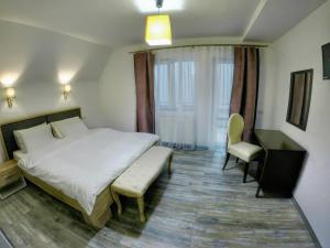 a bedroom with a bed and a chair and a window at Pensiunea Mirage in Iaşi