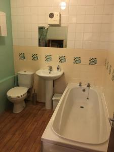 a bathroom with a tub and a toilet and a sink at Grace's HQ in Aldershot