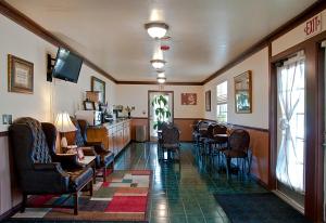 uma sala de espera com cadeiras, uma mesa e uma televisão em Regency Inn Eureka Springs em Eureka Springs