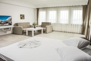 a bedroom with a white bed and a living room at King Hotel in Peje
