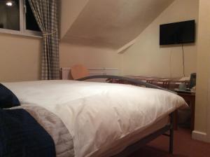 a bedroom with a bed and a table and a television at Alexander B&B in Hereford