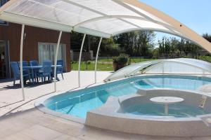 una sombrilla sobre una piscina con sillas y mesas en Gîte Du Puy de l'étang en Laruscade