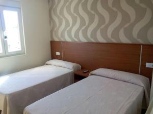 een kamer met 2 bedden en een raam bij Pensión Costiña in Noya