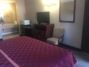 um quarto de hotel com uma cama, uma televisão e uma cadeira em America's Best Inn & Suites Eureka em Eureka