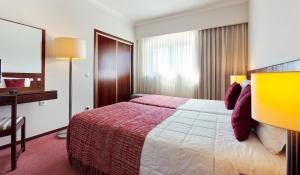 a hotel room with a large bed and a desk at Hotel Lux Mundi in Fátima