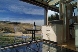 a kitchen with a table and chairs and a bottle of wine at Greystone PurePod in Waipara