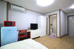 um quarto com uma cama e uma secretária com uma televisão em SB House em Suwon