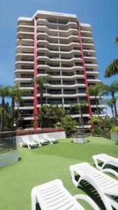 a large building with white lounge chairs in front of it at Alexander Holiday Apartments in Gold Coast