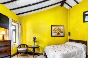 Dormitorio amarillo con cama, mesa y silla en La Posada De Los Cóndores, en Chaclacayo
