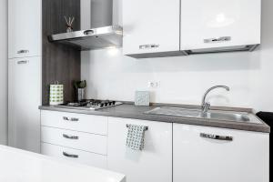 cocina blanca con fregadero y fogones en StayEasy Filzi11 - 3 Bedrooms, 2 baths - Central Station, en Milán