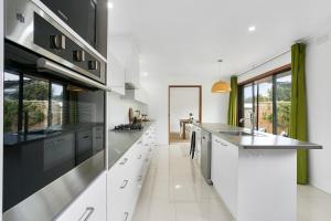 a kitchen with white cabinets and black appliances at Fairhills - beautifully styled in Rye