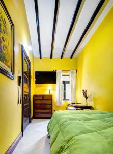 1 dormitorio con paredes amarillas y 1 cama grande en La Posada De Los Cóndores, en Chaclacayo