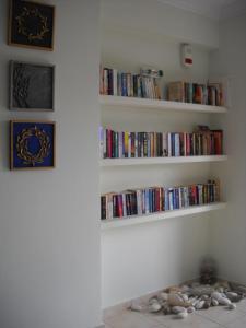 ein Zimmer mit weißen Regalen voller Bücher in der Unterkunft Olive Bay Hotel in Ayia Evfimia