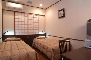 a bedroom with two beds and a table and a window at Yokohama Minatomirai Manyo Club in Yokohama