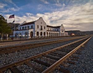 a white building with an american flag next to train tracks at Shady Motel in Caliente