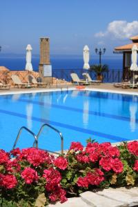 a swimming pool with red flowers and the ocean in the background at Sea View Village in Vasilikos