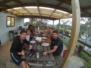 een groep mensen die aan een picknicktafel zitten bij Pukenui Holiday Park in Pukenui