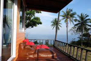 a leather couch sitting on a balcony with palm trees at Love Koh Tao Villa in Koh Tao